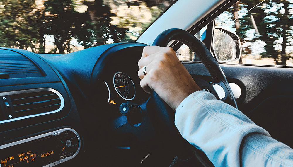 person holding the steering wheel of a car