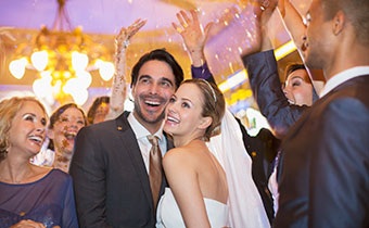 Bride and Groom cheek to cheek on the dance floor surrounded by guests