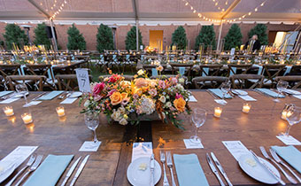 wedding reception tables setup with floral arrangements and table settings under a tent